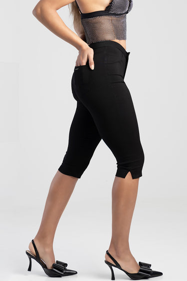 woman wearing black capri denim trousers with back pockets and small side slits, paired with black heeled sandals