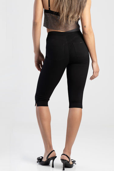 back view of a woman wearing black denim trousers with two rear pockets and small side vents at the hems by blue jean traders