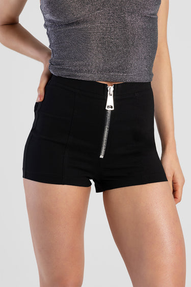woman wearing black high waist shorts with a large silver zipper at the front