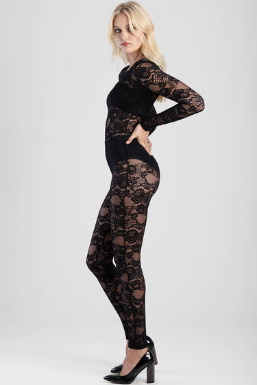 woman wearing Blue Jean Traders black lace jumpsuit with long sleeves, sheer floral pattern, and black heels.