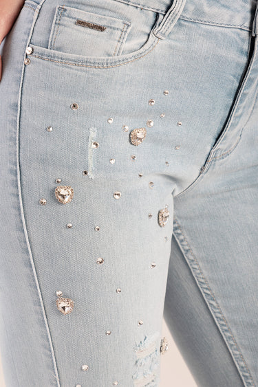 close up of light wash denim jeans with rhinestone studs and heart shapes on the thigh