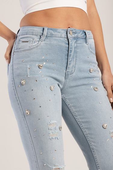 light wash jeans with rhinestone studs and distressed patches on the front, belt loops and button closure visible on a model
