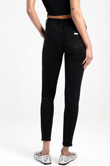 back view of a model wearing black skinny jeans with two back pockets and a small label on the right, paired with a black
