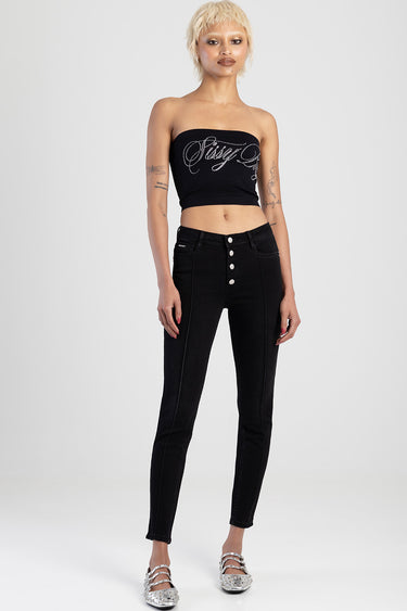woman wearing black skinny jeans with a high waist and five front buttons, paired with a black strapless top with