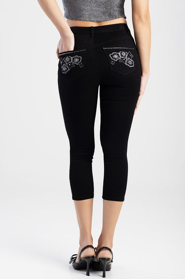 back view of black capri jeans with white embroidered floral pockets and studs