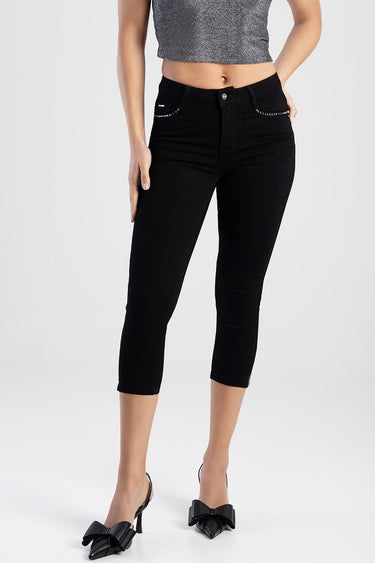 black capri jeans with rhinestone trim on the front pockets, slim fit, mid rise, worn with a grey cropped top and black bow