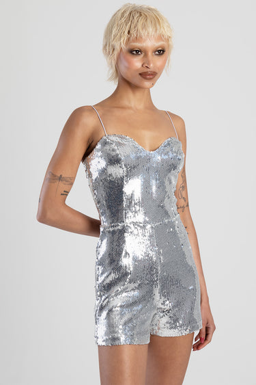 model wearing a silver sequin playsuit with thin spaghetti straps and a fitted short silhouette