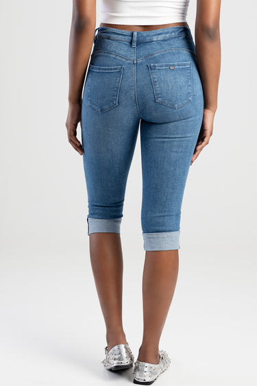 back view of a woman in light blue denim capri jeans with rolled cuffs and two back pockets, brand tag on the right pocket.