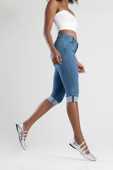 woman in blue denim capri jeans with rolled cuffs, white cropped top, silver perforated flats