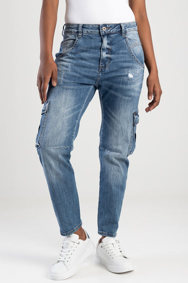 woman wearing blue denim cargo pants with distressing and side pockets, paired with white sneakers and a white top