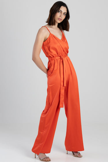 woman in a bright orange wrap belt jumpsuit with wide legs by blue jean traders