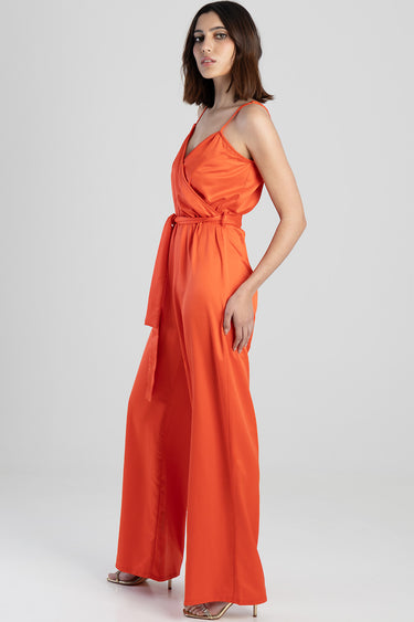 model wearing an orange wrap jumpsuit with a belted waist and wide legs, thin shoulder straps