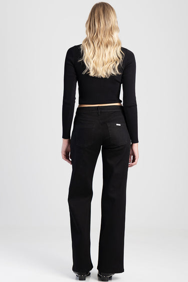 back view of a woman in black wide leg jeans and a black ribbed cropped sweater