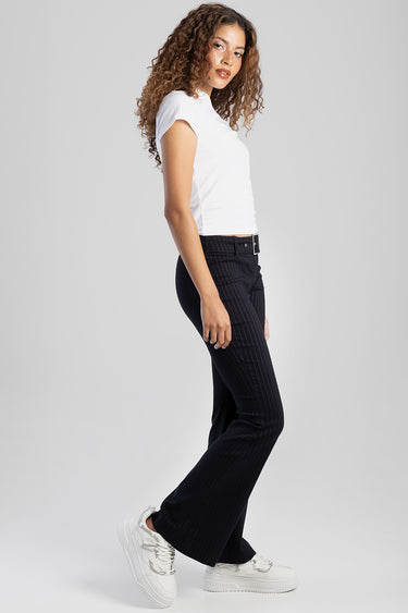 woman in navy pinstripe trousers and a white short sleeve top standing in profile with white sneakers