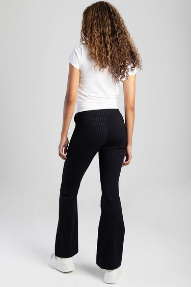 woman wearing a white t shirt and black pinstripe pants, back view, white sneakers