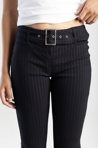 woman wearing black pinstriped trousers with a rhinestone belt buckle