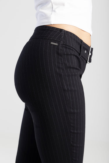 black pinstripe pants with a silver chain belt, worn by a model in a white top, Blue Jean Traders
