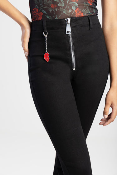 black slim fit jeans with a front silver zipper and dangling lip charm, paired with a floral top