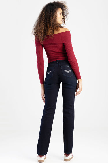 back view of a model in dark wash jeans with winged pocket embroidery and a red off the shoulder top