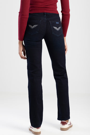 back view of a person wearing dark indigo straight jeans by Blue Jean Traders with rhinestone wing designs on back pockets