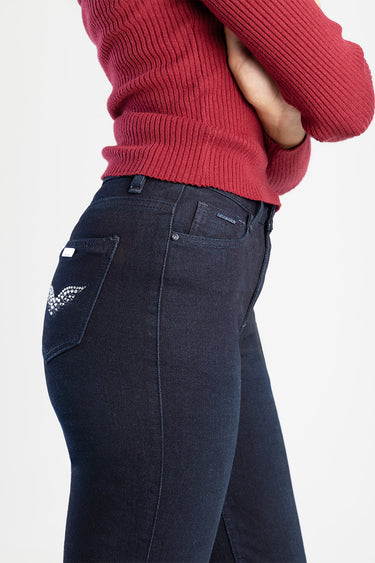 woman wearing a red knit sweater and dark navy jeans with rhinestone wing embroidery on the back pocket