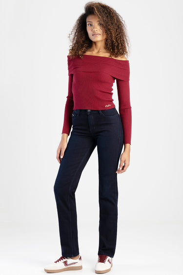 woman wearing burgundy off the shoulder knit top and dark blue straight jeans with white sneakers