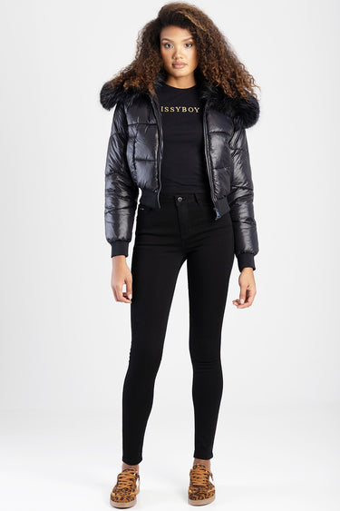 woman in black skinny jeans, a glossy puffer jacket with fur collar, and leopard print sneakers