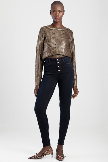 woman in dark indigo skinny jeans with a metallic gold knit sweater and leopard print flats