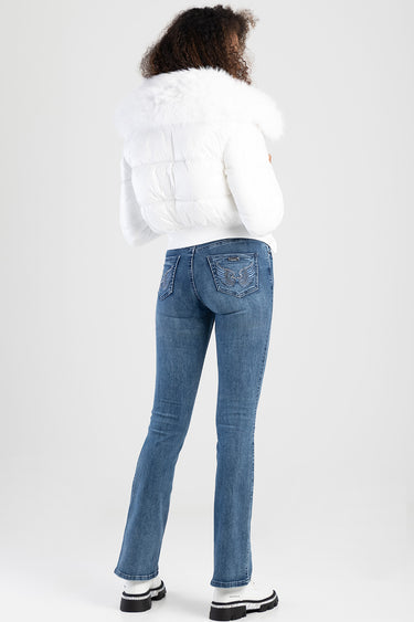 rear view of blue jeans with decorative back pockets and light wash, paired with a white puffer jacket with a large fur