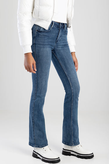 woman wearing blue bootleg jeans with a white puffer jacket and white platform shoes