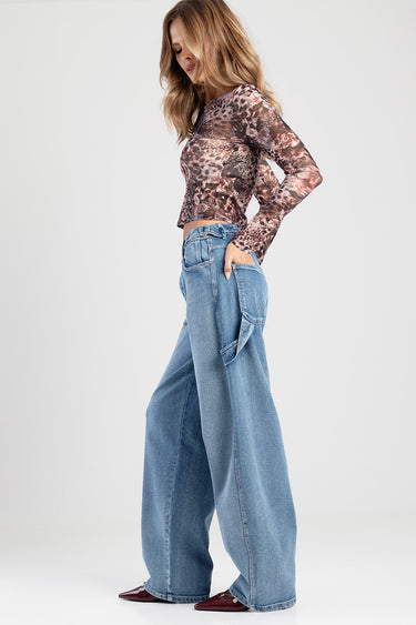 woman wearing a leopard print long sleeve crop top and light blue wide leg jeans, studio pose