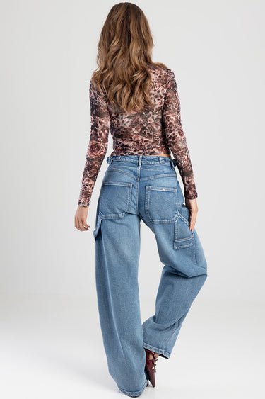 back view of a woman wearing light blue wide leg jeans with large back pockets and side cargo pockets, paired with a floral