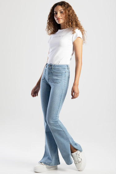 woman wearing light blue skinny flare jeans, white t shirt and white sneakers