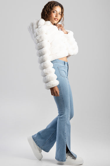 woman in white faux fur coat and light blue flare jeans side view