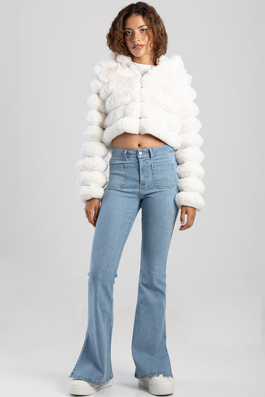 model wearing light wash skinny flare jeans with a cropped white fluffy coat