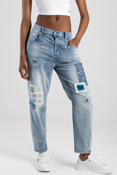 woman wearing light blue straight jeans with colorful patchwork panels on the legs and light distressing