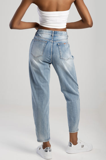 back view of a person wearing light wash denim jeans with rear pockets and white sneakers