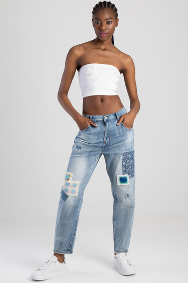 model wearing blue jean traders patchwork straight jeans with colorful square patches and white sneakers, paired with a