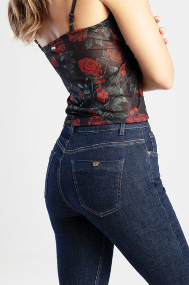 woman wearing dark blue skinny jeans with yellow stitching and a back pocket logo, paired with a red rose floral top