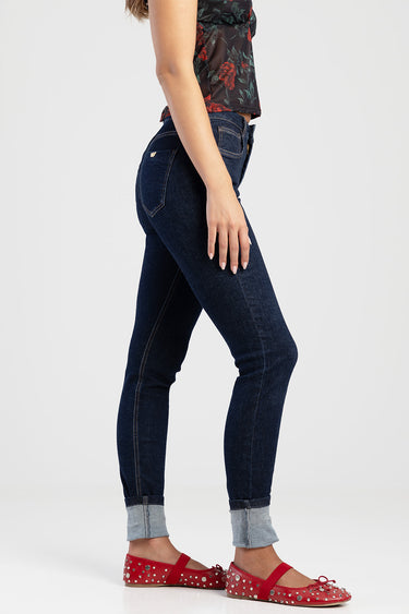 woman in dark indigo skinny jeans with rolled cuffs and red studded flats, floral top