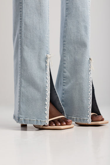 Blue Jean Traders jeans in light wash with lace trim slits at the hems paired with beige sandals