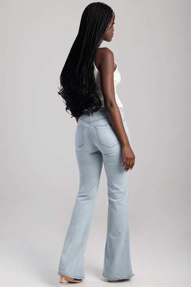 woman wearing light blue bootleg jeans, back view, long braids, neutral studio background