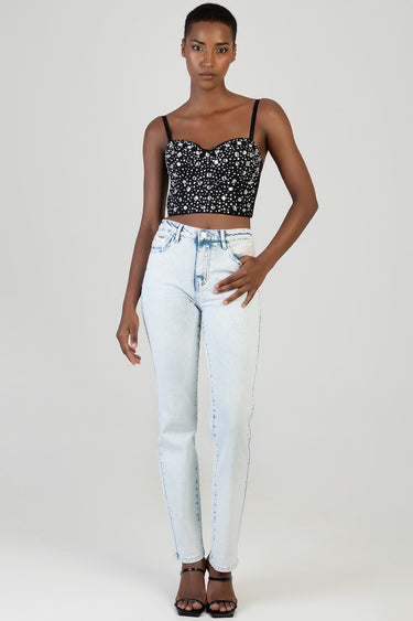 woman wearing a black sequined cropped top with thin straps and light wash stovepipe jeans