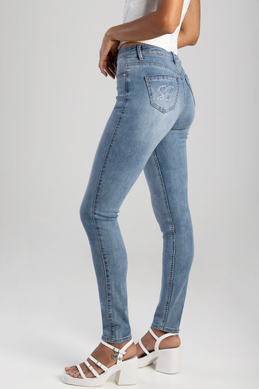 woman wearing light blue skinny jeans with embroidered butterfly on the back pocket, back view, white heeled sandals