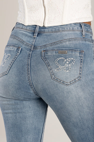 back view of light blue skinny jeans with butterfly embroidery on back pockets and a metal brand plaque