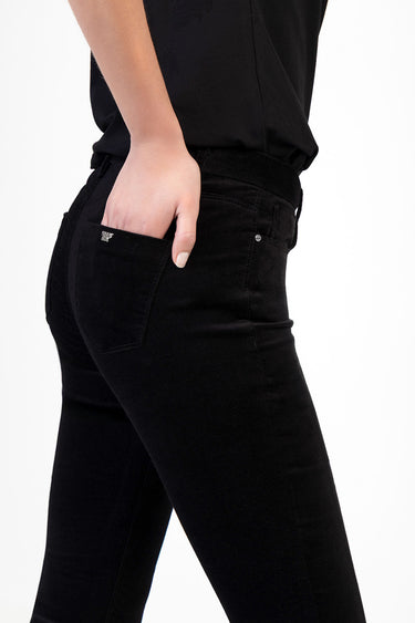 woman wearing black skinny pants; back pocket features a small metal badge from blue jean traders
