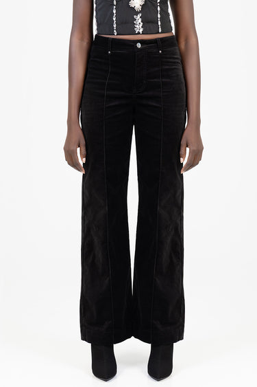 woman wearing black velvet wide leg pants with a high waist and front seam details, paired with heeled boots