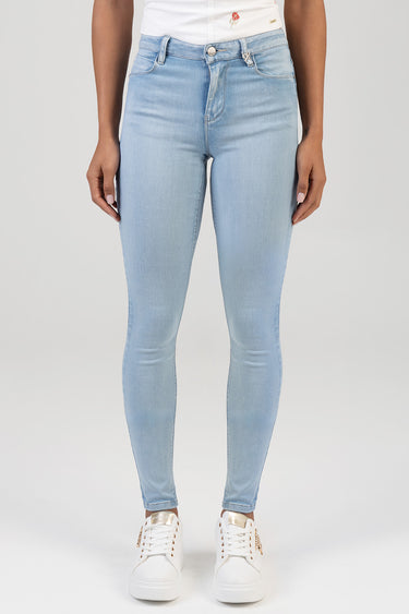 model wearing light blue skinny jeans from blue jean traders with white sneakers, front view shows five pockets and button