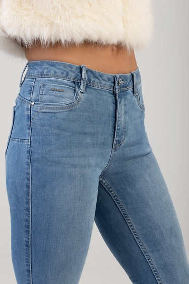 woman wearing light wash skinny jeans with belt loops and front pockets; small metal brand tag on the front pocket