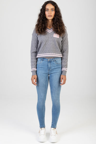 woman wearing light blue skinny jeans with a gray cable knit sweater and white sneakers